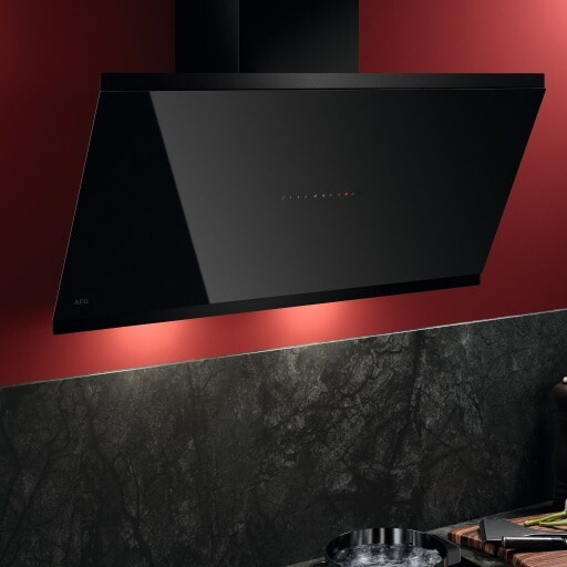 Angled black glass AEG chimney extractor hood on a red wall