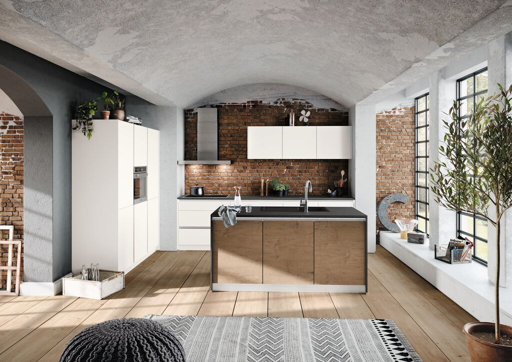 Handleless white kitchen with a timber island, exposed brick wall and vaulted ceiling