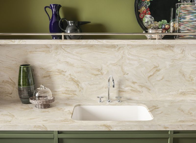 Corian worktop with an integrated white sink and coved upstand against olive green cabinetry