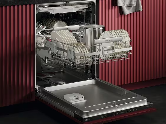 Fully integrated AEG dishwasher open in a ribbed red kitchen run